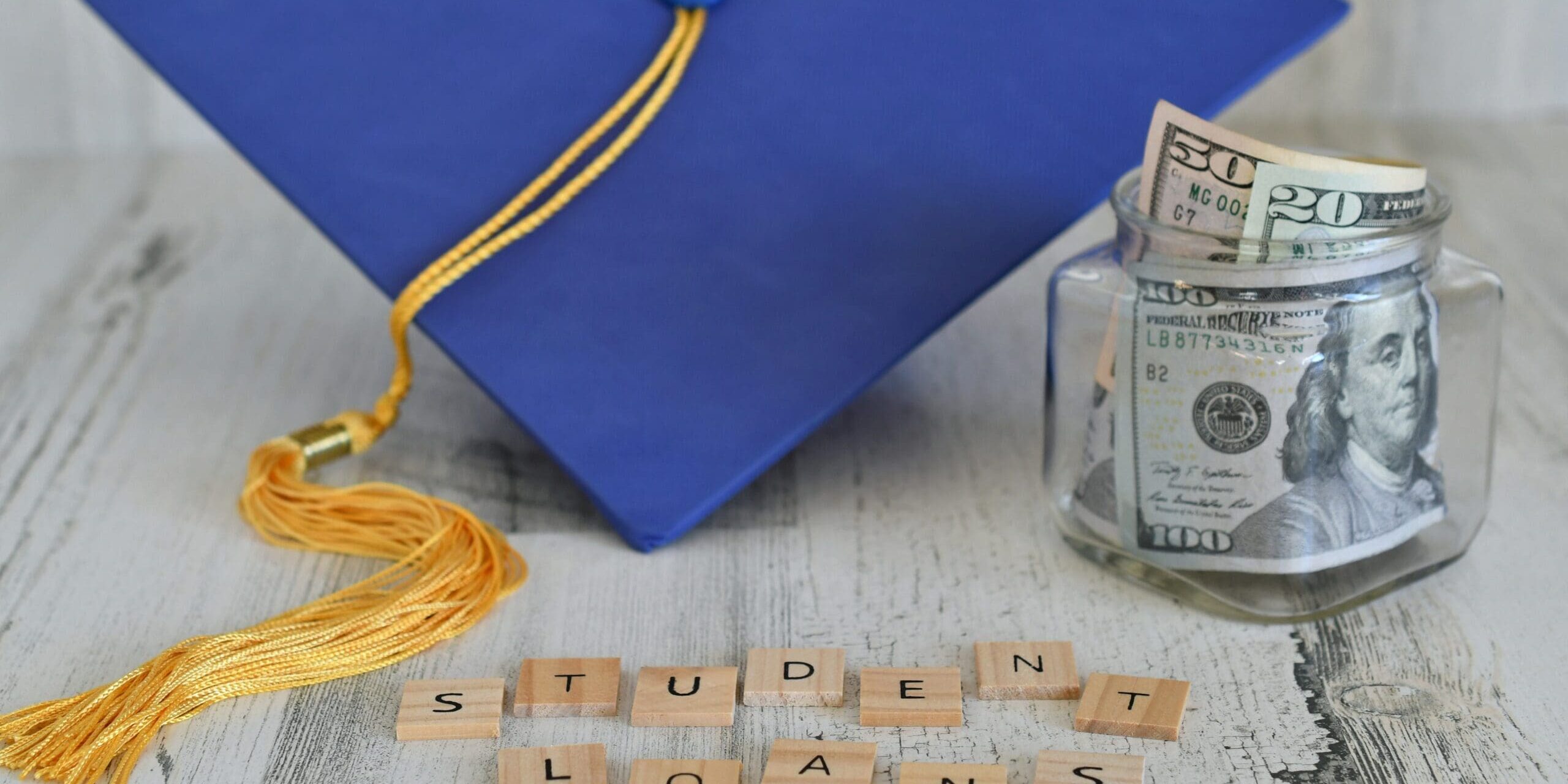 student loans written in scrabble pieces and a graduation cap